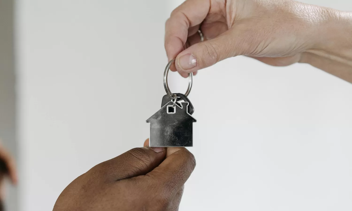 Hands holding keys above and below with a house on the keyring